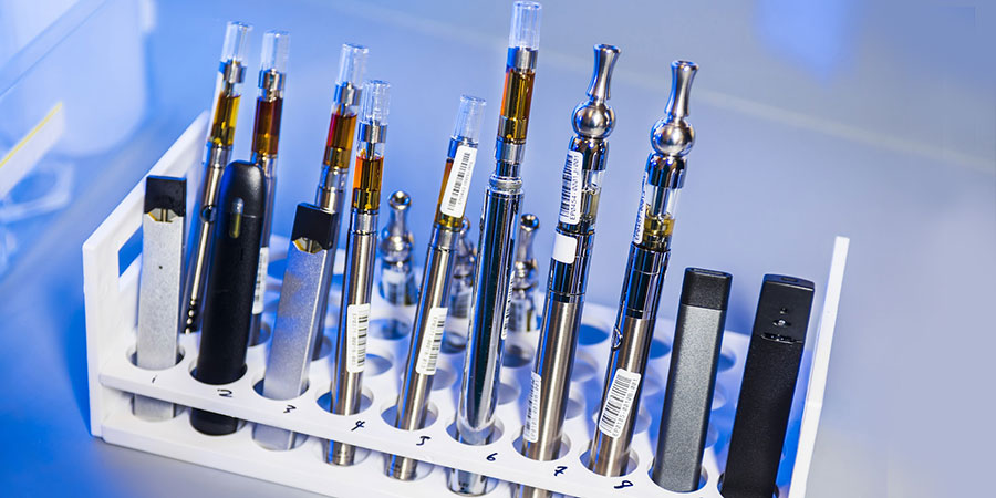white rack with several vape e-cigarette devices on top of a table
